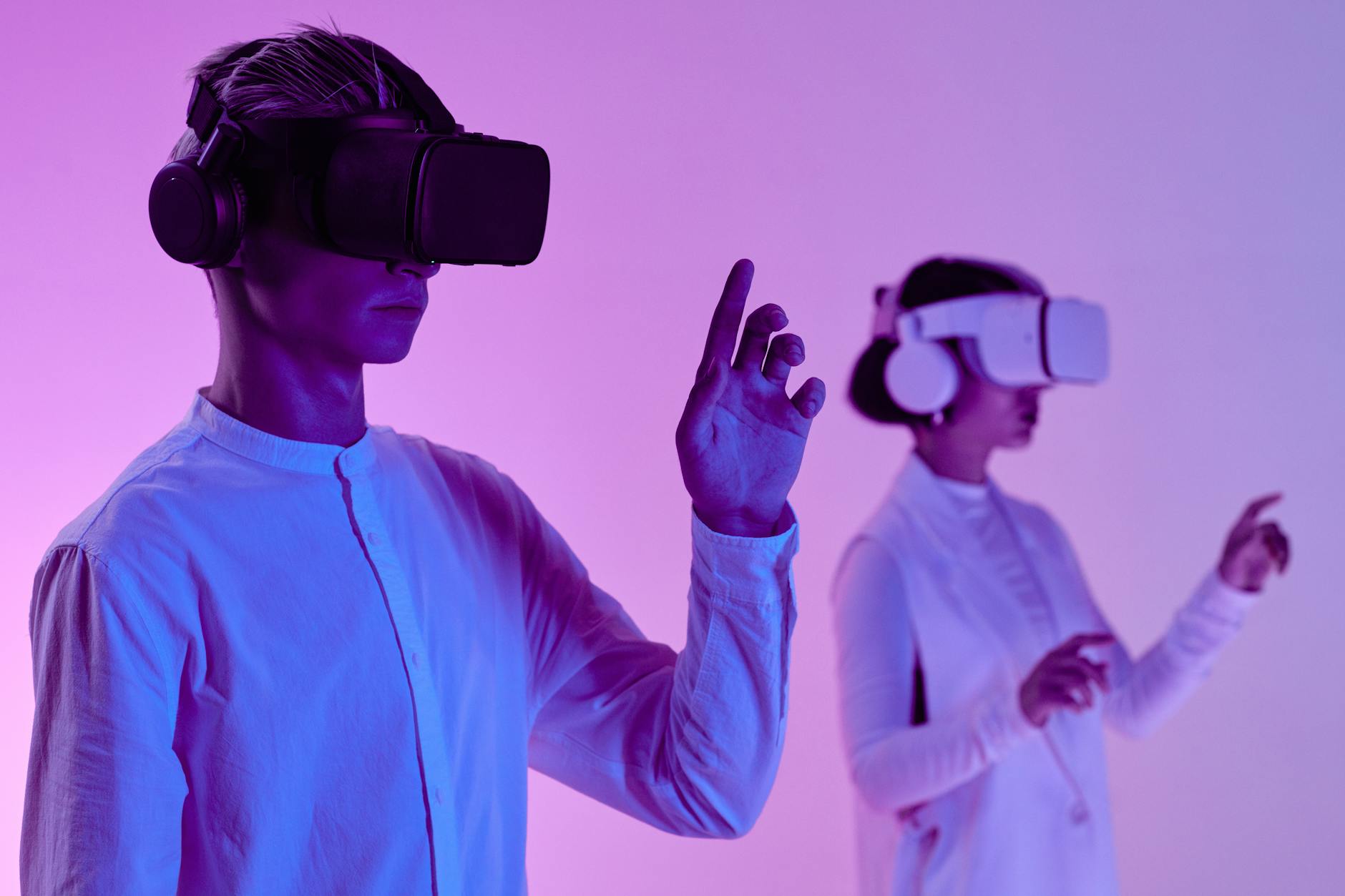 man and woman in vr goggles and headphone standing in studio in purple lighting